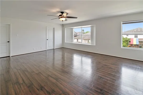 a view of an empty room with wooden floor and a window