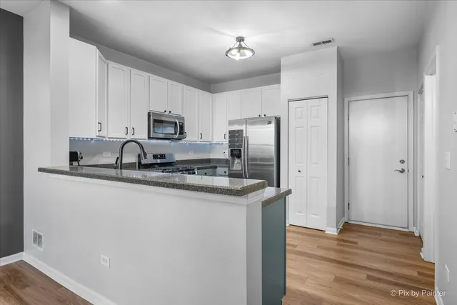 a kitchen with stainless steel appliances granite countertop a refrigerator a stove a sink and a microwave