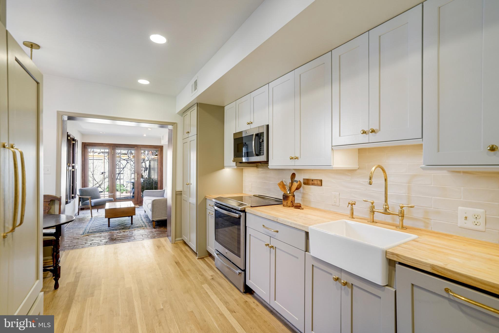 817 Duke Street Alexandria, VA 22314 - Photo 12 of 39 a kitchen with a sink dishwasher stove and white cabinets with wooden floor