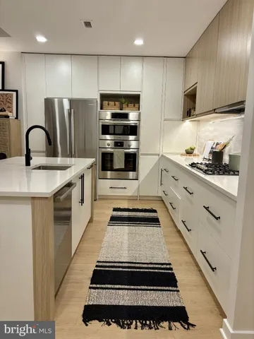 a kitchen with stainless steel appliances a stove a sink and a refrigerator
