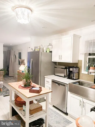 a kitchen with stainless steel appliances kitchen island granite countertop a table chairs and a refrigerator