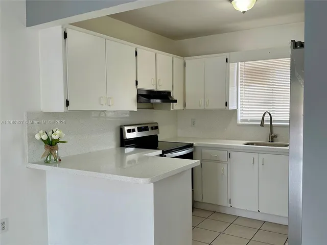 a kitchen with cabinets appliances a sink and a window