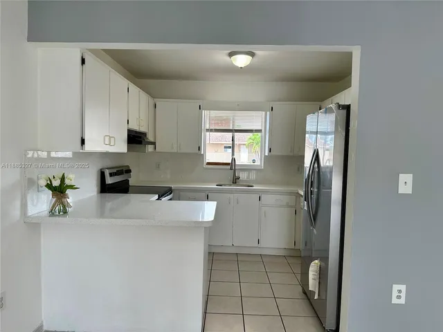 a kitchen with a sink a refrigerator and cabinets
