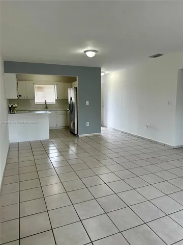 a large white kitchen with a white checkered floor
