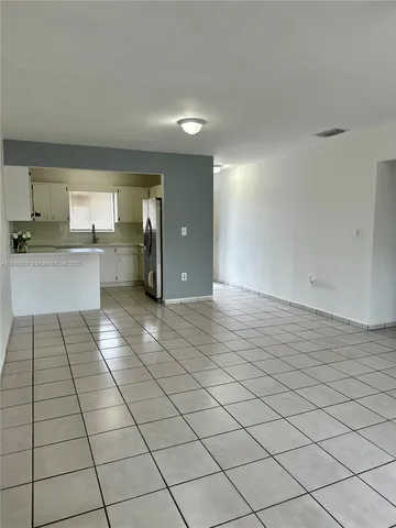 a large white kitchen with a white checkered floor a sink and a stove top oven