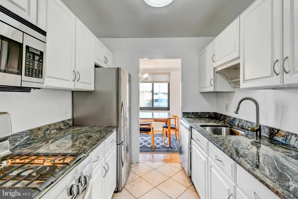 a kitchen with granite countertop a sink a stove and cabinets