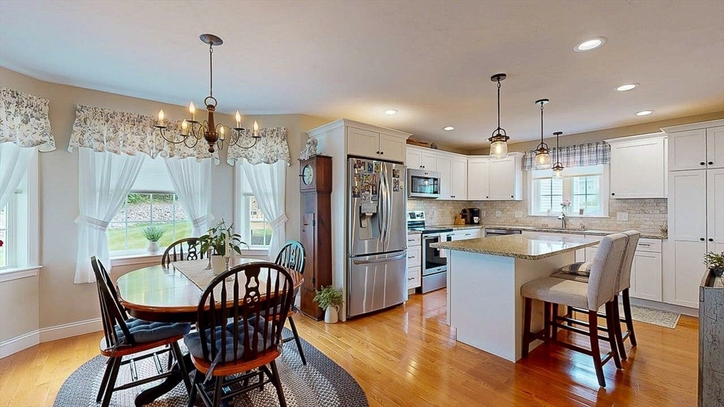 67 Cobblestone Lane, Unit 63 Worcester, MA 01606 - Photo 11 of 38 a kitchen with stainless steel appliances kitchen island a dining table chairs and white cabinets