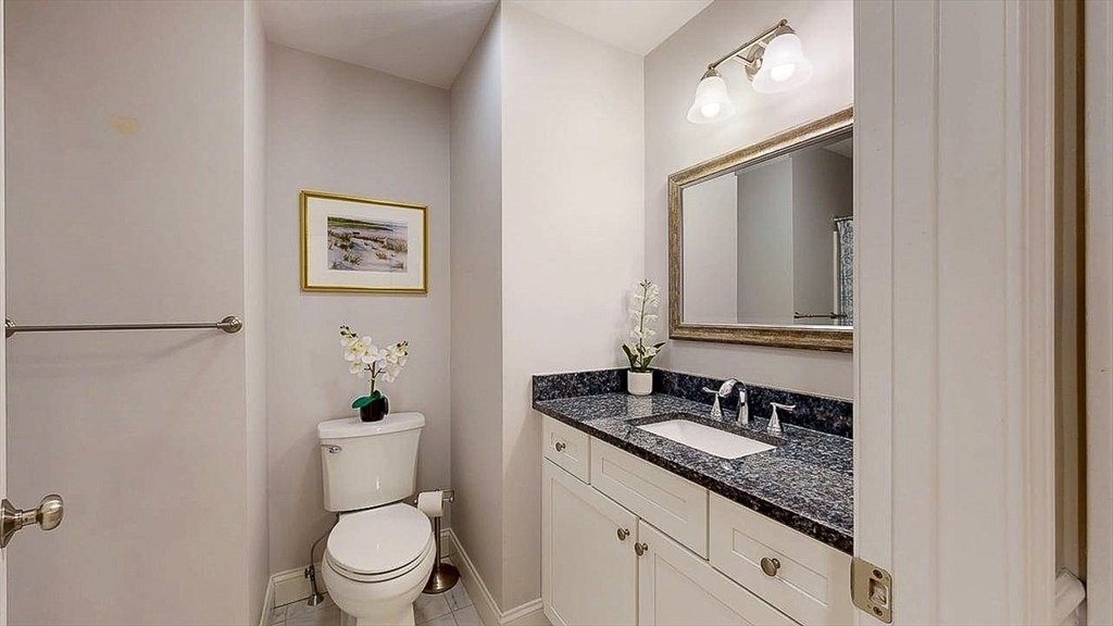 67 Cobblestone Lane, Unit 63 Worcester, MA 01606 - Photo 30 of 38 a bathroom with a granite countertop toilet a sink and mirror