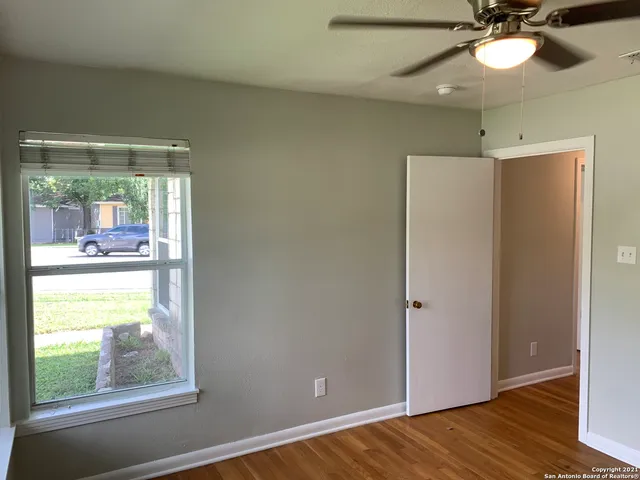 a view of empty room with wooden floor and fan