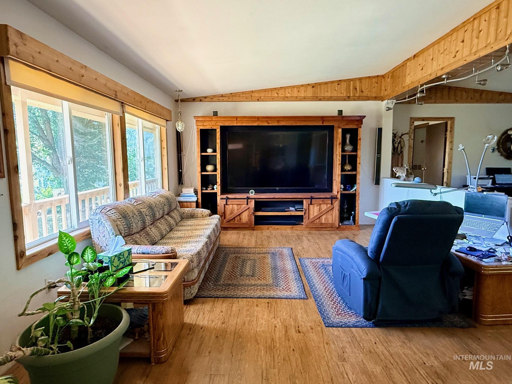 35322 River Road Lenore, ID 83541 - Photo 5 of 42 Living area featuring wood-finish flooring, a large custom entertainment center, and multiple windows offering ample natural light