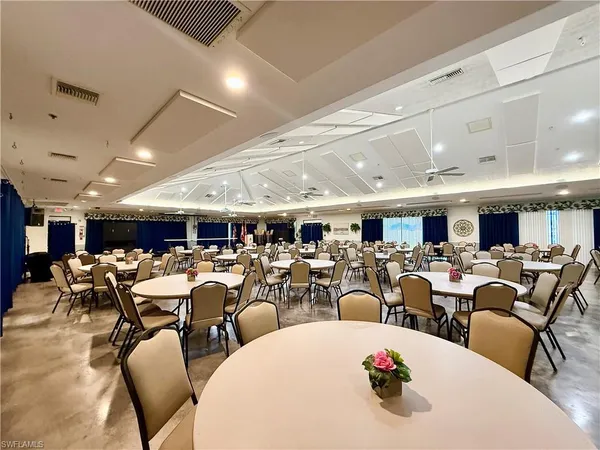 a large room with lots of white furniture a chandelier a large window and a projector