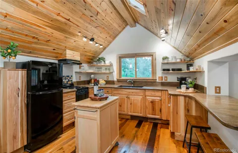 a kitchen with stainless steel appliances granite countertop a refrigerator a sink dishwasher a stove and white countertops with wooden floor