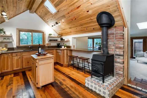 a kitchen with stainless steel appliances granite countertop a stove refrigerator a dining table and chairs with wooden floor