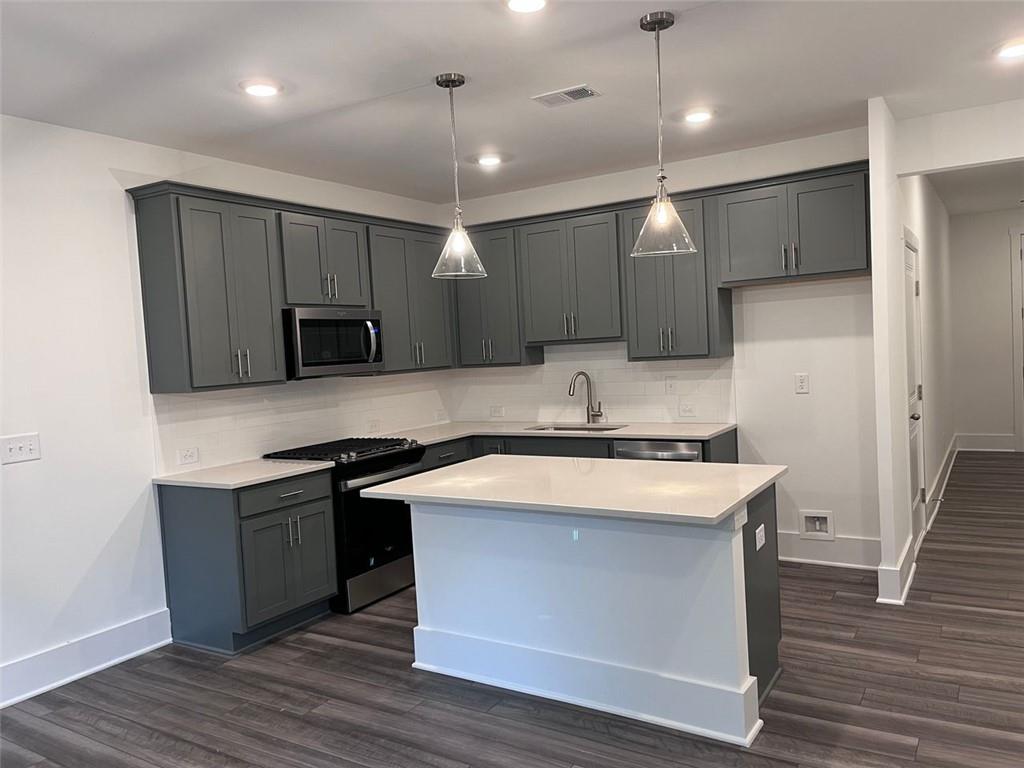 1654 Florence Run Northwest Atlanta, GA 30318 - Photo 5 of 41 a kitchen with kitchen island stainless steel appliances a sink cabinets and wooden floor