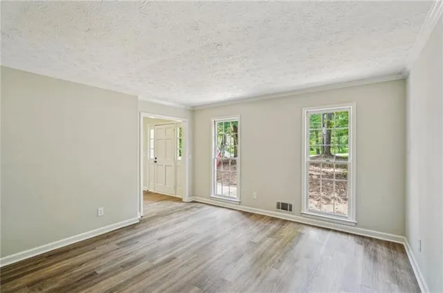 an empty room with wooden floor and windows