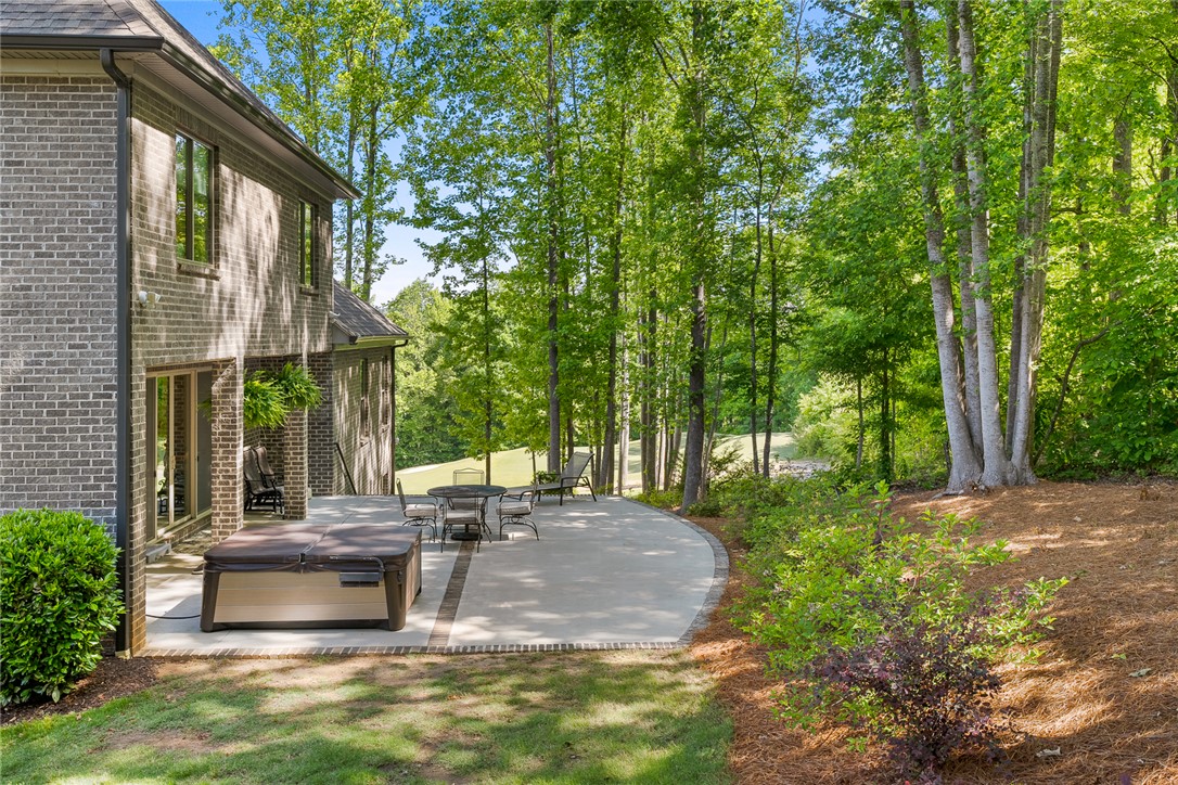 140 Turnberry Road Anderson, SC 29621 - Photo 31 of 44 This inviting patio offers relaxation with a hot tub, surrounded by lush trees and ample outdoor space.