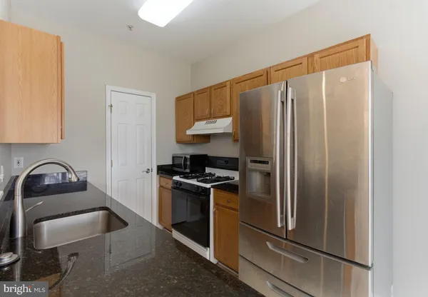 a kitchen with stainless steel appliances granite countertop a sink a stove and a granite counter tops with white cabinets
