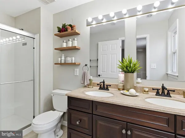 a bathroom with a sink a toilet a mirror and shower