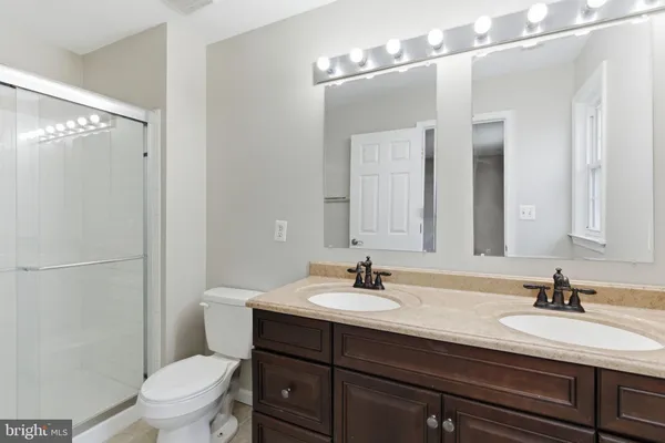 a bathroom with a sink a toilet a mirror and shower
