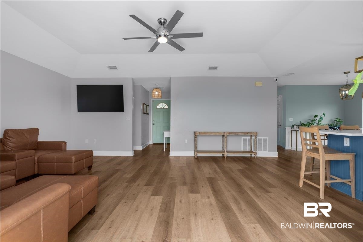 8952 Sherman Road Foley, AL 36535 - Photo 12 of 41 Spacious living area featuring wood-finish flooring, a contemporary ceiling fan with integrated lighting, and a vaulted ceiling