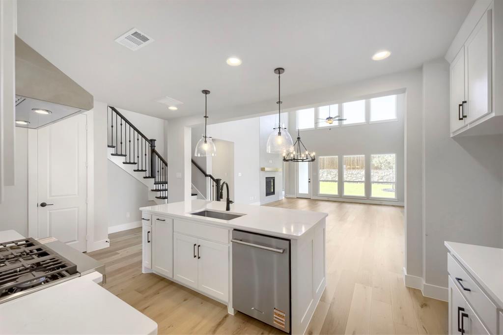 800 Blackberry Road Haslet, TX 76052 - Photo 9 of 28 Open-concept kitchen with a large island featuring a built-in sink, stainless steel dishwasher, and pendant lighting