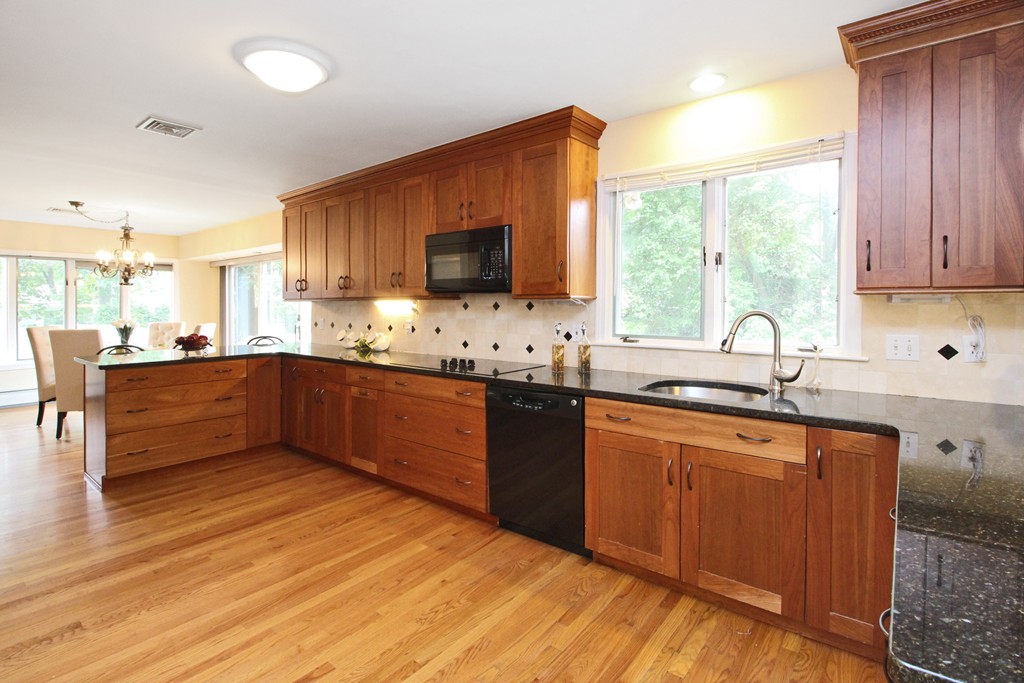 83 Spring Valley Road Belmont, MA 02478 - Photo 9 of 30 a kitchen with stainless steel appliances kitchen island granite countertop a sink dishwasher a dining table and chairs with wooden floor