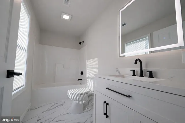 a bathroom with a sink a toilet and a large mirror