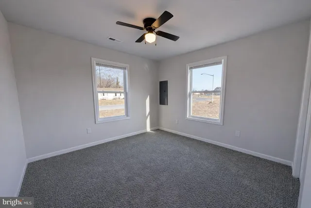 an empty room with windows and ceiling fan