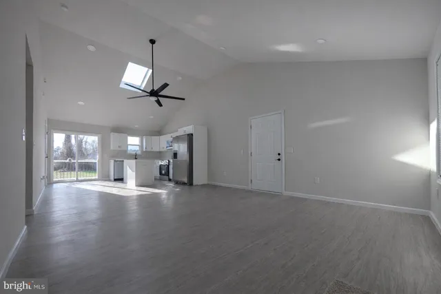 an empty room with wooden floor ceiling fan and windows