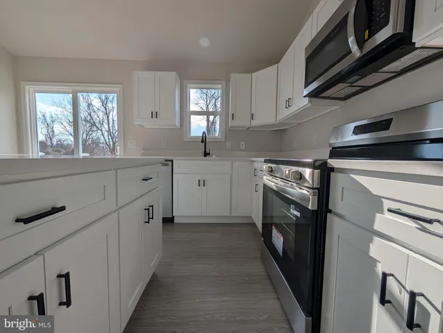 a kitchen with cabinets stainless steel appliances a sink and a window