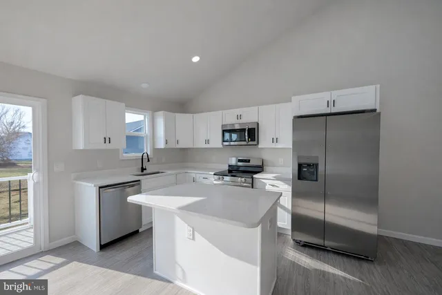 a kitchen with stainless steel appliances a sink a stove a refrigerator cabinets and a window