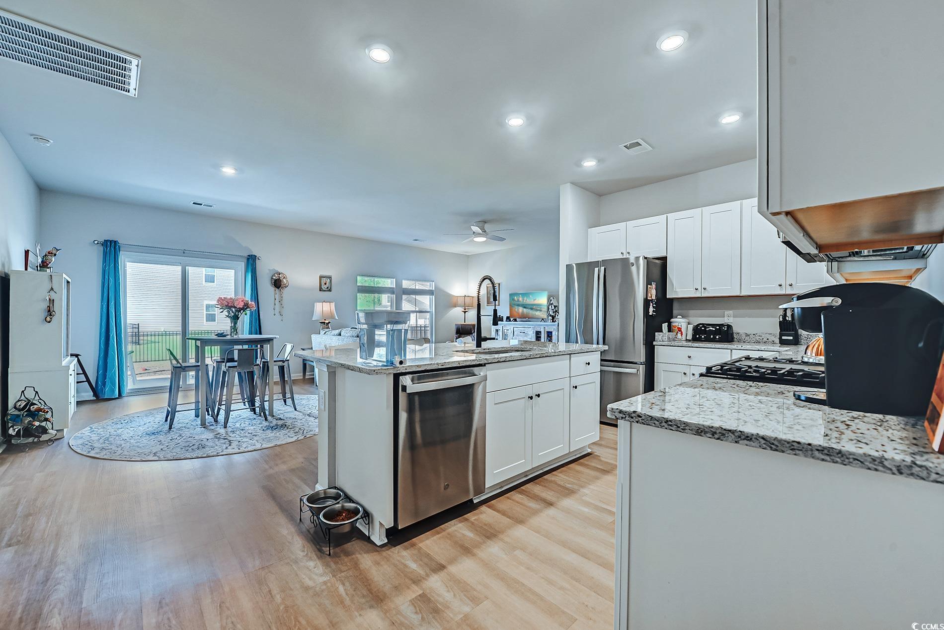 177 Fox Rae Drive Conway, SC 29526 - Photo 5 of 39 Kitchen with light stone counters, white cabinetry, appliances with stainless steel finishes, an island with sink, and light wood-style flooring