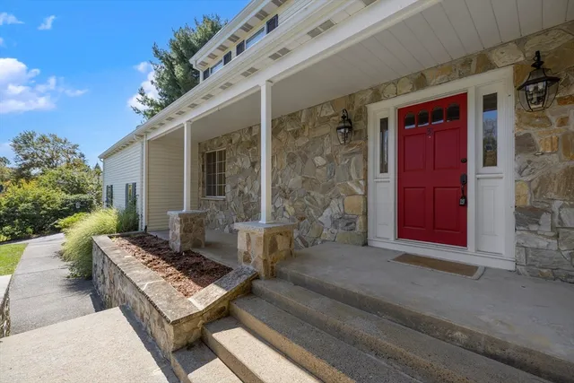 a white house with red door and tree