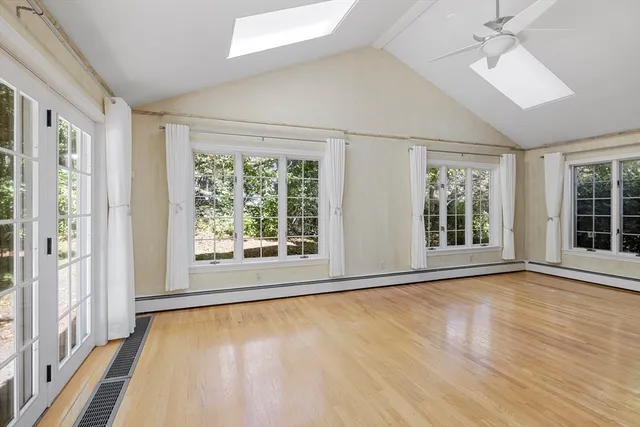 a view of an empty room with a window and wooden floor