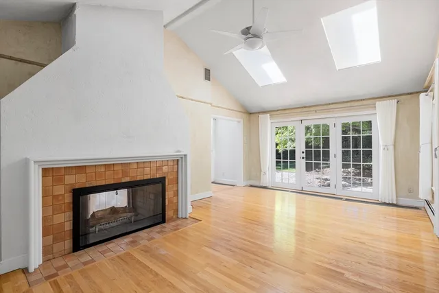 a view of an empty room with wooden floor fireplace and a window