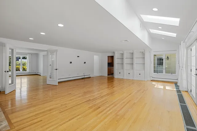 a view of empty room with wooden floor and window