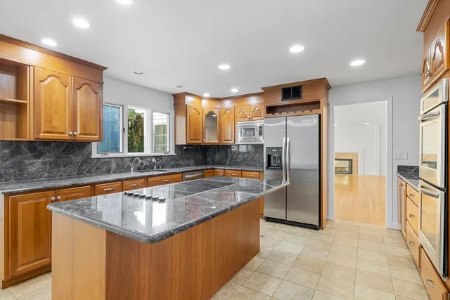 a kitchen with stainless steel appliances granite countertop a sink a stove a refrigerator a washer and dryer
