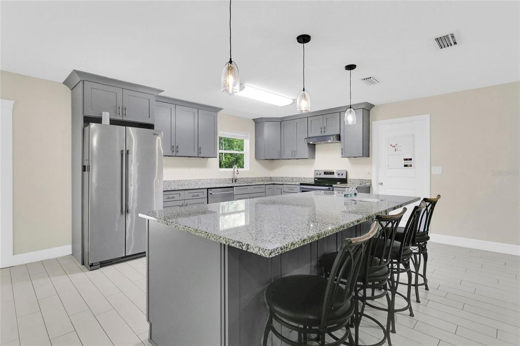 1801 West Highway 329 Citra, FL 32113 - Photo 4 of 34 a kitchen with stainless steel appliances granite countertop a sink a stove a refrigerator and island with wooden floor