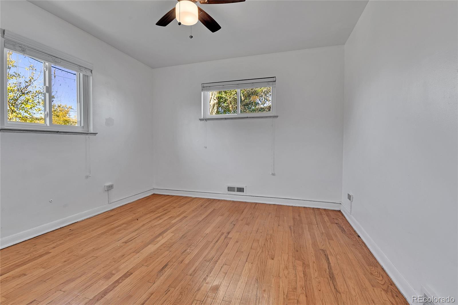 3591 Pontiac Street Denver, CO 80207 - Photo 14 of 26 an empty room with a window and wooden floor