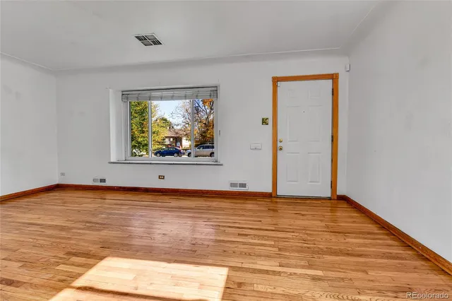 a view of an empty room with window and wooden floor