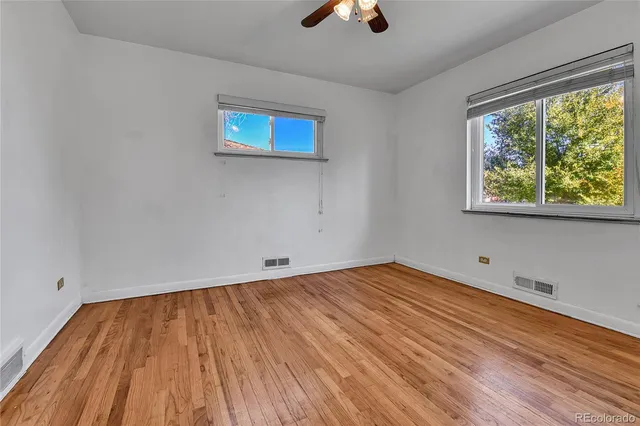 a view of empty room with wooden floor and fan