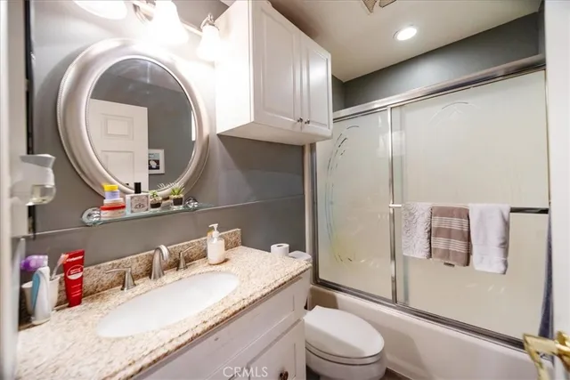 a bathroom with a granite countertop sink mirror vanity and toilet