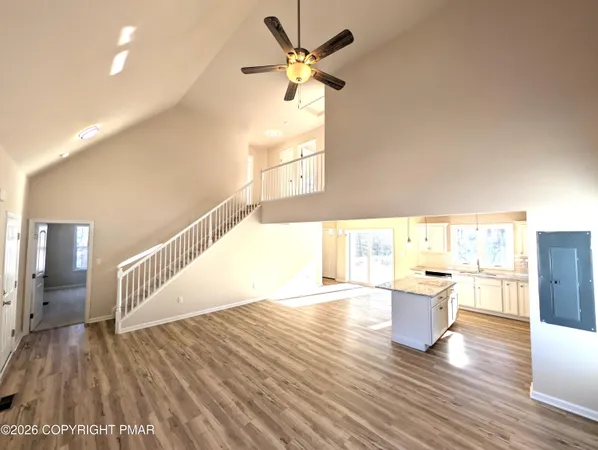 a view of an empty room with wooden floor fireplace and a window