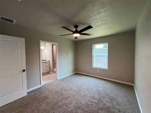 an empty room with windows and ceiling fan