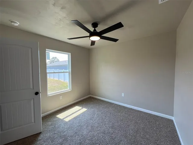 an empty room with a window and a fan