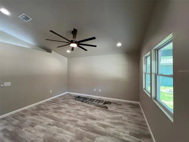 an empty room with ceiling fan and window