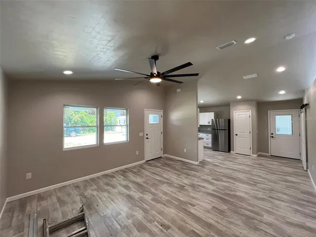 a view of an empty room with window and wooden floor