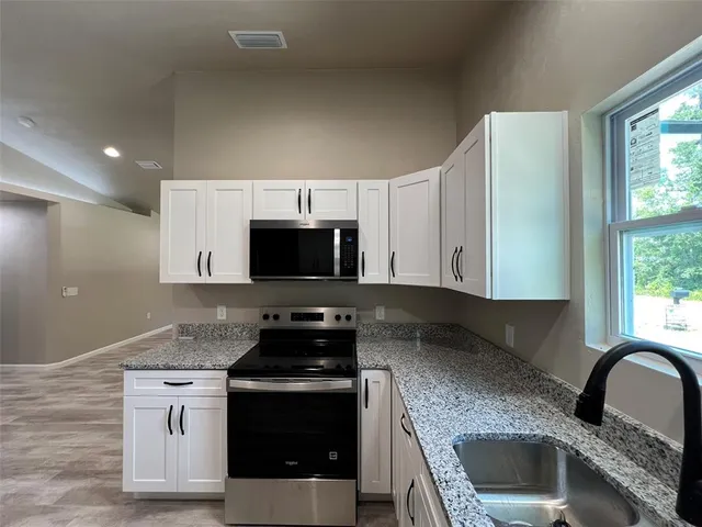 a kitchen with stainless steel appliances granite countertop a stove a sink and a microwave
