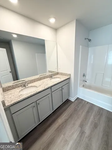 a spacious bathroom with a granite countertop sink a mirror and a bathtub