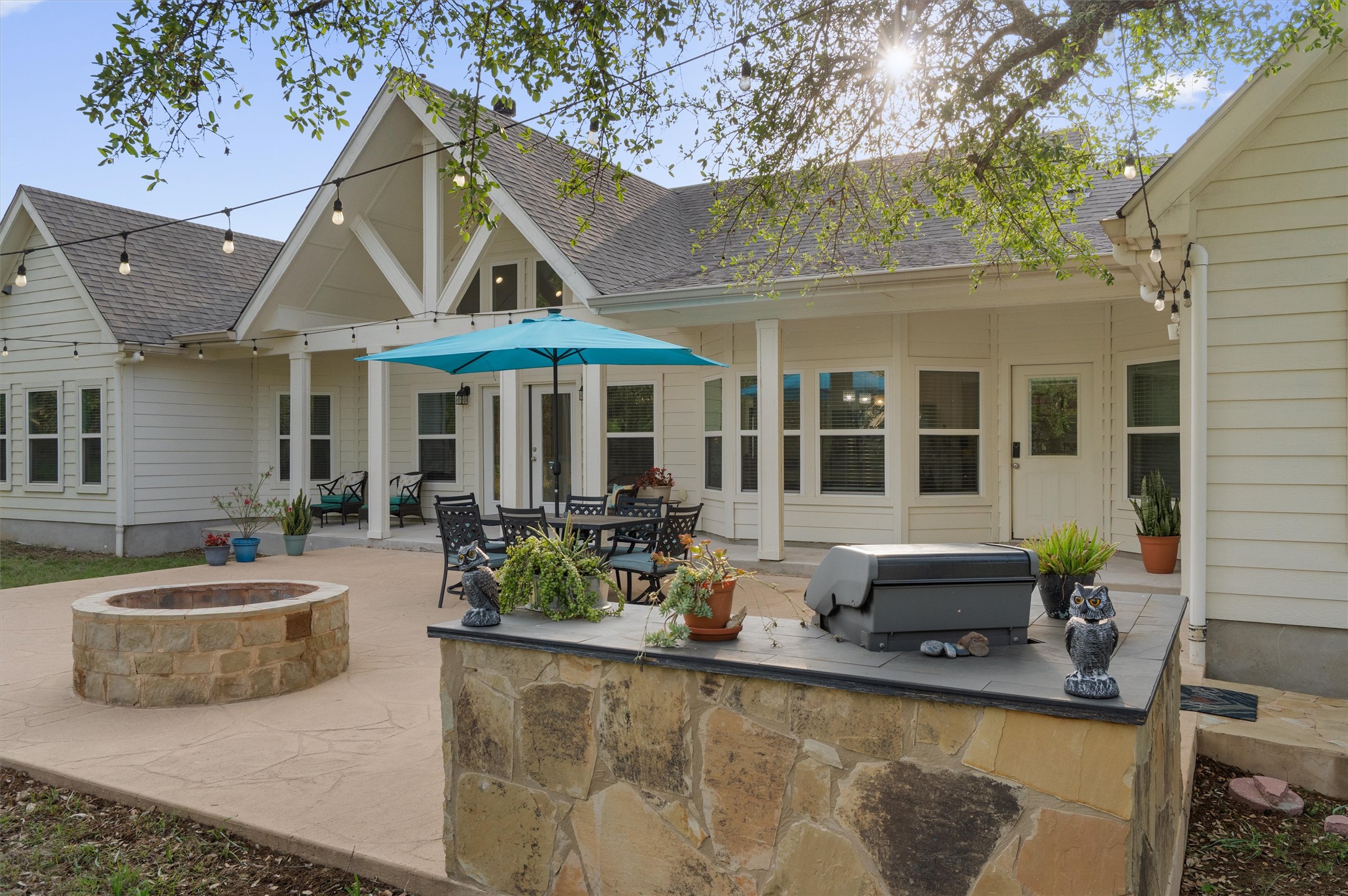 13105 Rooster Springs Road Austin, TX 78737 - Photo 22 of 38 The property features an outdoor patio with a stone fire pit, a built-in stone counter, and a dining area under a covered porch